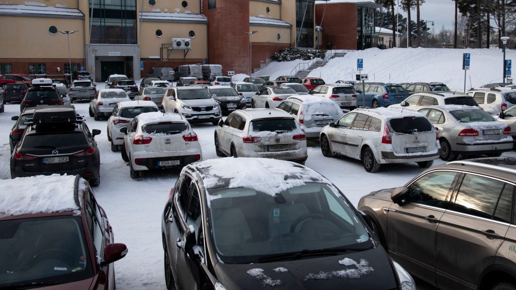 Vintertäckta bilar på en stor parkering.